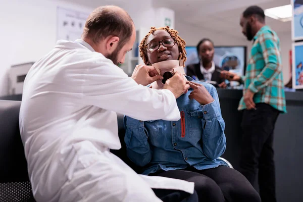 Врач Осматривающий Африканскую Американку Воротником Шее Сидящую Приемной Больницы Пациент — стоковое фото