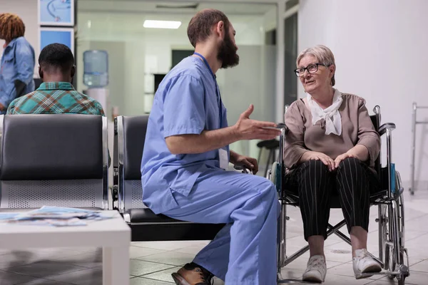 Male Nurse Consulting Woman Chronic Disability Hospital Waiting Area Medical — Foto de Stock