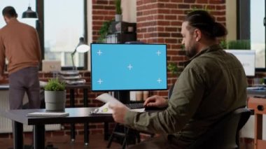 Ofis çalışanı yeşil ekran ile bilgisayarda yazıyor, izole edilmiş krom anahtar telif alanı ve masaüstü monitöründe boş model şablonu ile çalışıyor. Başlangıçta yeşil renkli anahtar gösterimi.