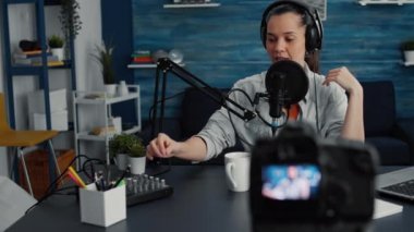 Profesyonel mikser kullanarak sesi ayarlarken mikrofonda izleyicilere hitap eden çekici bir sosyal medya etkileyicisi. Yaratıcı dijital içerik yaratıcısı ev stüdyosunda podcast yapıyor.