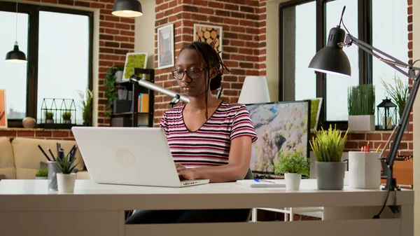 Female freelancer working on laptop to send email remotely from home, using online network connection. Businesswoman doing remote work on computer, sitting at desk. Freelance job.