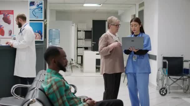 Medical Assistant Doing Consultation Senior Patient Hospital Reception Area Looking — Stockvideo