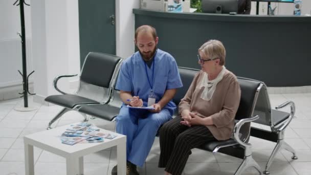 Arzthelferin Berät Alte Patienten Der Wartezimmer Lobby Sitzt Der Rezeption — Stockvideo