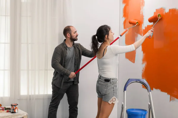 Young Couple Using Orange Color Paint Wall Roller Paintbrush Home — Φωτογραφία Αρχείου