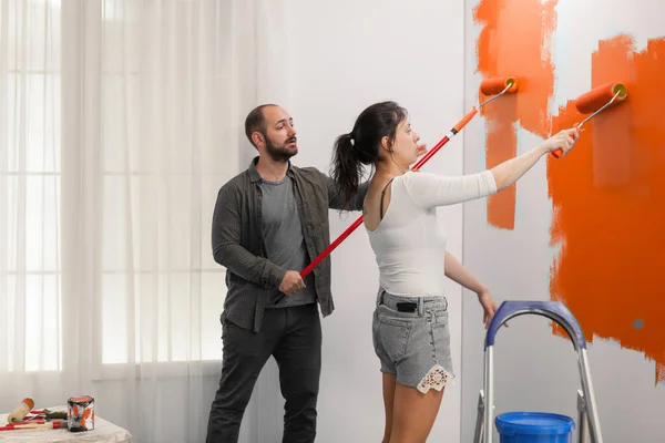 Οικογένεια Χρησιμοποιώντας Πορτοκαλί Χρώμα Για Βάψετε Τον Τοίχο Ρολό Και — Φωτογραφία Αρχείου