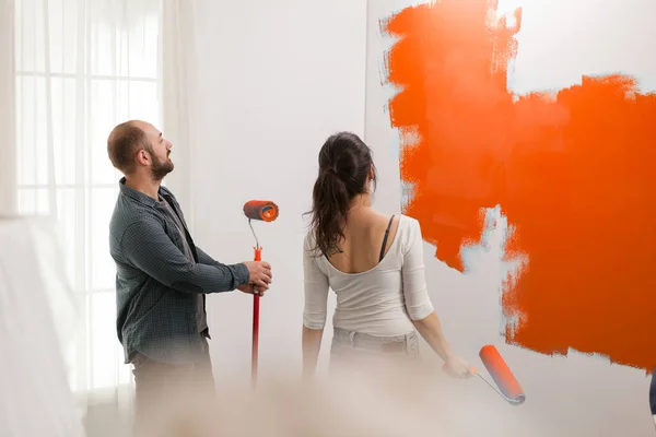 Άνδρας Και Γυναίκα Ζωγραφική Πορτοκαλί Χρώμα Χρησιμοποιώντας Χρώμα Για Διακοσμήσετε — Φωτογραφία Αρχείου