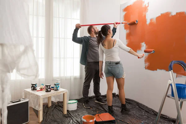 Pareja Feliz Pintando Pared Con Pintura Naranja Redecorando Apartamento Con —  Fotos de Stock