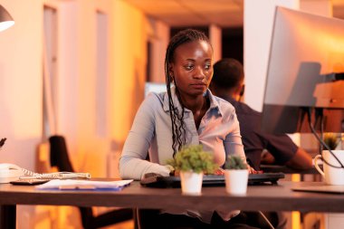 Afrika kökenli Amerikalı serbest çalışan bilgisayar üzerinde proje verileri yapıyor, araştırma bilgilerini e-posta üzerinde iş raporu oluşturmak için kullanıyor. Gün batımında bilgisayar ekranındaki çevrimiçi evraklara bakıyorum..