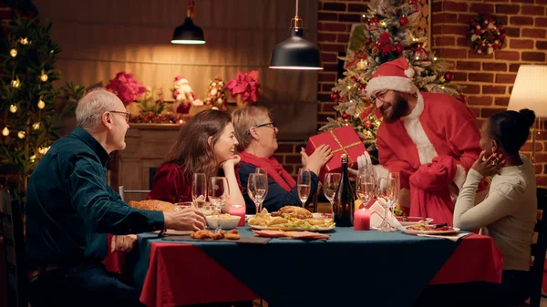 Festive Man Disguised Santa Claus Giving Family Members Gifts While — Stock Fotó