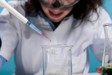 Tehlikeli testler yaparken cam deney şişesine kan damlatan çılgın laboratuvar çalışanlarını kapatın. Manyak görünüşlü manyak biyokimyacı toksik kimyasal bileşikleri denemek için damlatıcıyı kullanıyor..