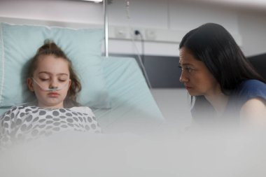 Hasta kızın yanında oturan huzursuz ebeveyn pediatri koğuşunda hastaneye kaldırıldı. Annesi yanında otururken, küçük kız sağlık merkezinde dinleniyor..