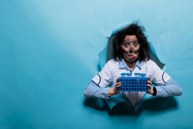 Tuhaf görünüşlü, garip saçlı ve plastik test tüpleriyle doluyken dilini dışarı çıkaran çılgın bir kimyager. Kirli suratlı ve şapşal suratlı çılgın bilim adamı örneklerle dolu duruyor..