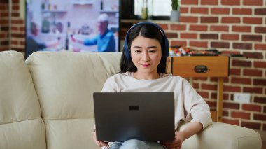 Happy woman in virtual online videoconference with manager while working remotely at home in living room . Smiling person talking with coworker on videocall digital meeting on laptop. Tripod shot