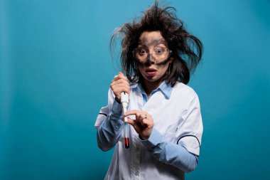 Laboratuvar patlamasından sonra deli bir kimyager cam test tüpünü deneysel kimyasal bileşiklerle doldururken maddeleri karıştırıyor. Kan örneğiyle dolu cam tüplü çılgın bilim adamı..