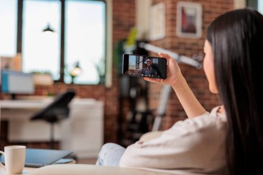 Otantik meşgul Asyalı kadın video görüşmesi yapıyor. İnternet üzerinden iletişim kuruyor. Mobil uygulamadan merhaba internet teknolojisi sallıyor.