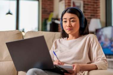 Asyalı kadın evde online film seyrediyor abonelik platformu, eğlence filmi dizisi internet teknolojisi dizisi dizüstü bilgisayarda yeni medya dijital uygulaması yayınlıyor