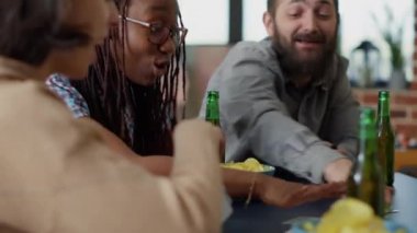 Rekabetçi arkadaşlar birlikte oyun oynuyor, oturma odasında eğlenmek için stratejiyi kullanıyorlar. Mutlu erkekler ve kadınlar eğlenmek için gülüyor ve oyun oynuyorlar..