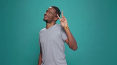 Pozitif model, barış işaretini kameranın önünde gösteriyor, başarıya ve zafere inanıyor. Stüdyoda V şeklindeki sembolün reklamını yapan erkek, barışçıl bir zafer hareketi yapıyor..