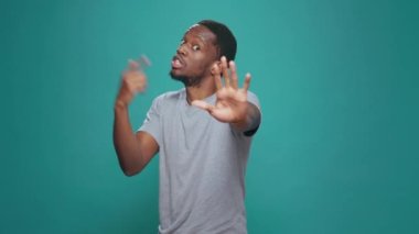 Portrait of person doing talk to the hand rejection gesture, expressing refusal and disapproval. Negative man advertising no sign and disagreeing, showing dislike symbol in studio.