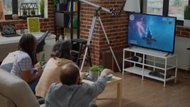 Oyun konsolunda oyun oynayan farklı arkadaş grupları, nişancı rekabetiyle eğleniyorlar. İnsanlar eğlence için TV ekranında siber uzay eylem yarışmasını seviyorlar.