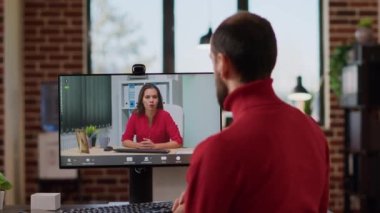 Uzaktan telekonferansta yöneticiyle konuşan genç bir işadamı internette konferans toplantısını kullanıyor. Yönetici, bir kadınla görüntülü konuşma yapıyor. Haberleşme..