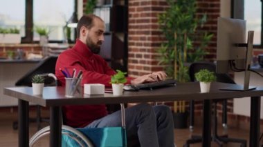 İş büyümesinde engelli bir yönetici masada bilgisayarla çalışıyor, tekerlekli sandalyede. Yürütme şirketi geliştirmek için finansal strateji planlayan erkek işçiler.