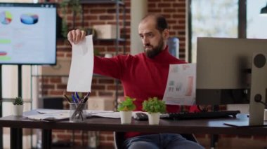 Financial analyst looking at documents with work statistics, creating business strategy for development. Young manager using data analysis on charts and graphs to be successful.