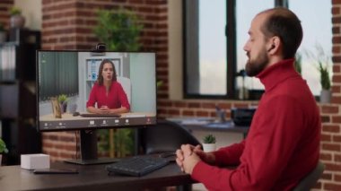 İş yerindeki video görüşmesine katılan erkek çalışan, bilgisayarla çalışıyor. Menajer, çevrimiçi video konferansında, monitörde kablosuz telekonferans kullanarak kadınla konuşuyor..