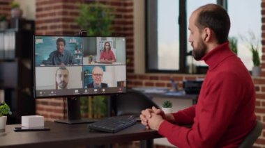 İş adamlarıyla video görüşmesine katılan bir ofis çalışanı, finansal büyüme hakkında konuşuyor. Erkek çalışan uzaktan video konferans sohbetini kablosuz iletişimi tartışmak için kullanıyor. Üçayak atışı.