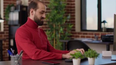 Genç yetişkin telefonlara cevap veriyor ve şirket işinde bilgisayar üzerinde çalışıyor. Lider internet ağındaki iş stratejisini planlarken akıllı telefonu uzaktan iletişim için kullanıyor.