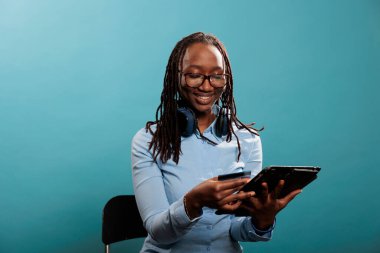 Dokunmatik ekran elektronik cihazı olan genç bir insan kredi kartıyla ödeme yapıyor. Modern tabletli mutlu, çekici bir kadın alışveriş merkezinin kredi kartıyla online ödeme yapıyor..