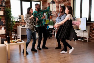 Dostluk yıldönümünde alkollü içecekler içerken kutlama yapan neşeli arkadaşlar. Çeşitli gençlerden oluşan bir grup şarap partisinde salonda dans ederek doğum günü kutluyor..