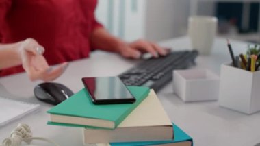 İş kadını ofisteki masada cep telefonunu kontrol ediyor, mesajlara bakıyor. Bilgisayarda satış istatistikleri ile finansal gelişim üzerinde çalışan kadın çalışan. El kamerasıyla. Kapat..