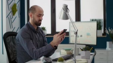 İstatistiklerle akıllı telefon uygulaması üzerinde çalışan finans asistanı, iş büyüme stratejisi için interneti taramak için mobil telefon kullanıyor. Erkek çalışanın ofiste araştırma sunumu.