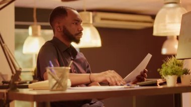 Şirket çalışanı, belgelerdeki iş verilerini analiz ediyor, şirket raporu ve web sunumu oluşturmak için evrak dosyalarını kullanıyor. Araştırma notları bilgileriyle çalışıyorum. El kamerasıyla..