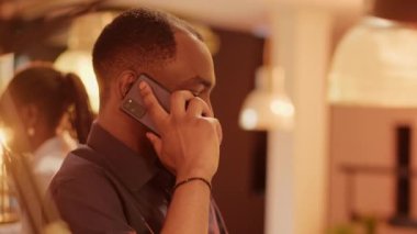 Ofis masasında cep telefonuyla konuşan Afrikalı Amerikalı bir adam, uzaktan konuşmak için internet üzerinden telefon hattı iletişimini kullanıyor. Akıllı telefondan uzaktan konuşma, çevirme numarası.