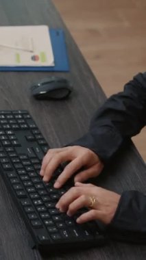 Vertical video Focus on programer hands typing code on keyboard while looking at computer screens with programming interface. System engineer sitting at desk with clipboard writing algorithm.