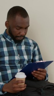 Dikey video: Çok ırklı bir grup insan iş görüşmesinde kuyrukta bekliyor, lobide askere alma belgelerini okuyor. Erkek ve kadın iş fırsatı için iş toplantısına hazırlanıyor.