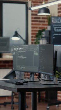 Boş yazılım geliştirme bürosunda programlama kodunu çalıştıran dikey video ekranları ve arka planda veri algoritmalarını ayrıştıran bilgisayarlar. Sinirsel ağ sunucuları veri olarak bulut hesaplama