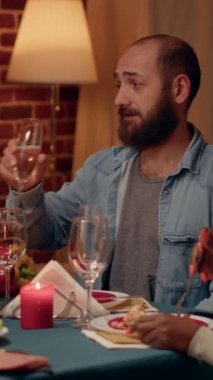 Dikey video: Kendinden emin bir adam, Noel yemeğinde köpüklü şarap içerken pozitif yaşlı bir kadınla konuşuyor. Neşeli aile üyeleri geleneksel Noel 'i geleneksel bir şekilde sıcak bir evde kutluyorlar.