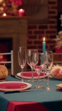 Vertical video: Empty interior of festive traditional Christmas dinner table with authentic decorative cutlery and dinnerware. Cozy and ornate looking living room with seasonal and positive style with