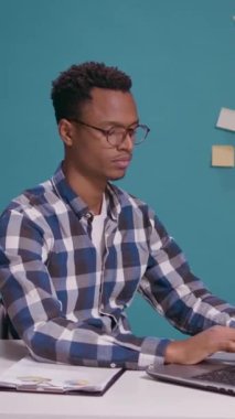 Dikey video: Afro-amerikan kişi iyi ve onay işareti gösteriyor ve elleri masada dizüstü bilgisayarın önünde. İyimser yetişkin reklam başarısı ve mükemmel tatmin hareketi..