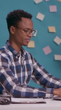 Dikey video: Şirket çalışanı, dizüstü bilgisayarla çalışırken işine ve patronuna saygı göstererek el üstünde askeri selam veriyor. İşçi reklamı asker jesti, selamlama müdürü..