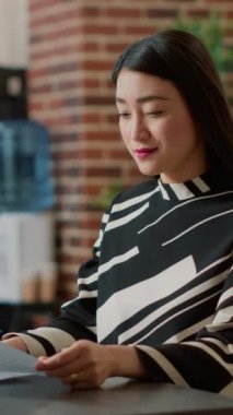 Vertical video: Portrait of female worker using recruitment papers to start job interview with candidates, finding person to hire for executive business work. HR employee looking at cv for career