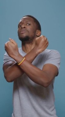 Dikey video: Memnuniyetsizlik gösteren ve silahlarla dur işareti yapan, kameranın önünde ret ve ret hareketi yapan kişi. Reddetme reklamındaki olumsuz adam sevmeme ve kırma sembolü..