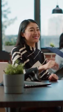 Dikey video: Asyalı işçi iş görüşmesinde iş teklifini ve kariyer fırsatını tartışmak için bayan başvuruyu karşılıyor. İnsan Kaynakları çalışanı CV 'ye bakıyor ve işe alım toplantısında kadınlarla görüşüyor..