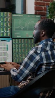 Vertical video: Male broker using forex trade exchange statistics on multiple monitors, working with market charts and real time stocks sales. Hedge fund profit share to buy and sell money. Tripod
