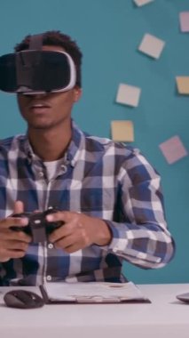 Dikey video: 3D etkileşimli simülasyonla sanal gerçeklik deneyiminin tadını çıkaran, joystick ve vr gözlüklerle video oyunları oynayan modern kişi. Oyuncu denetleyici, konsol ve gelecek teknolojisi kullanıyor