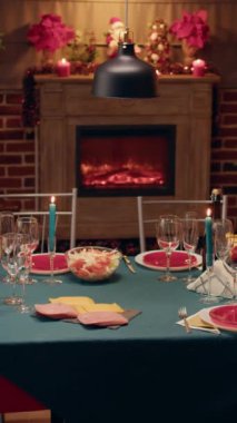 Dikey video: Noel 'de boş yemek masası dekore edilmiş oturma odasında Noel çelenkleri ve yemek takımlarıyla. Geleneksel ve otantik mevsim havası. Dini törenler düzenleniyor.