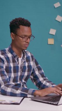 Dikey video: Öfkeli işçi dizüstü bilgisayardaki iş hatası yüzünden gergin hissediyor, masada agresif tepkiler veriyor. Serbest çalışma stratejisi üzerinde çalışırken rahatsız bir insan bağırıyor ve rahatsız oluyor.